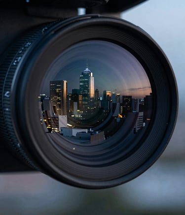 Close-up of a high-resolution drone camera lens reflecting a modern Latin American skyline at dusk, cinematic lighting with dark blue and greyish blue tones, shallow depth of field, professional and technical atmosphere.