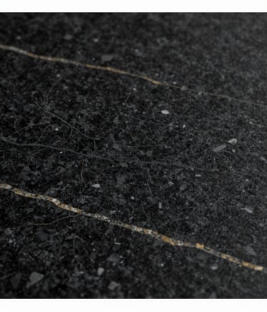 A close-up, high-resolution shot of a luxury black granite slab with subtle gold and white veins, reflecting soft studio lighting. Minimalist and exclusive aesthetic, incorporating the brand colors #0D0D0D and #A18A6A.