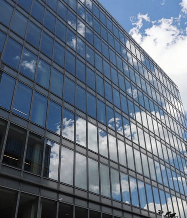 A crisp, wide-angle shot of a modern glass-walled office building in a North American business district, with perfectly clean windows reflecting a deep blue sky and white clouds, emphasizing professional clarity and detail.