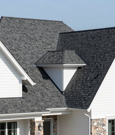 A wide-angle photography shot of a luxury North American home with a newly installed dark gray architectural shingle roof. The house has white siding and stone accents. Professional lighting, clean composition, bright midday sun.