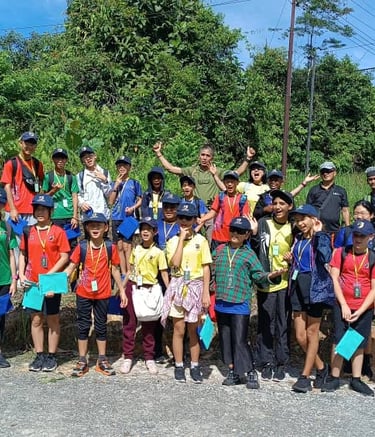 a group of students standing in front of a lost borneo tours bunting