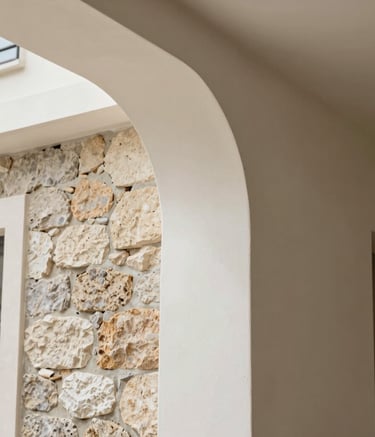Detail of high-quality renovation work in a French residence, showing a perfect transition between a stone wall and modern plaster, natural soft lighting, aesthetic and clean architectural composition.