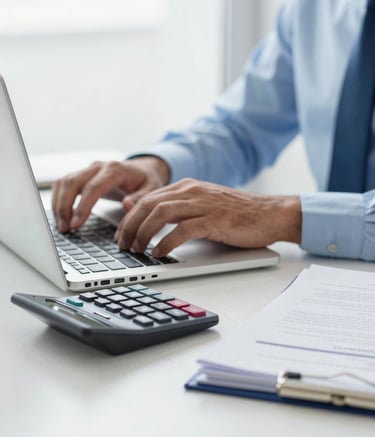 Close-up of a professional accountant's hands working on a laptop in a bright South American / Brazilian office. A professional calculator and a neat stack of documents are on the desk. The lighting is soft and airy, featuring a Cloud White and Pale Blue color palette.