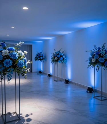 Photography of a peaceful and modern funeral home interior in Peru, with clean architecture and soft deep blue lighting. The composition is wide and elegant, featuring light steel blue floral arrangements on minimalist stands.