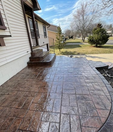Custom stamped concrete patio with ashlar slate pattern and curved border in a residential backyard.