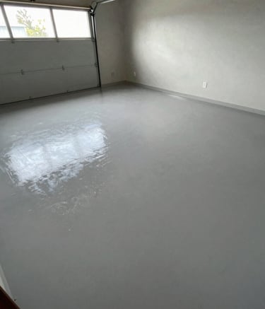 Freshly applied light grey epoxy garage floor coating with a glossy reflective finish.