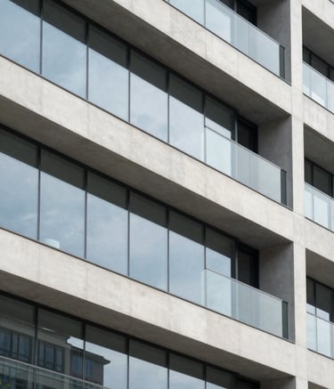 A close-up architectural detail of a modern building facade featuring clean geometric lines, glass panels, and smooth concrete surfaces. The lighting is bright and airy, reflecting a Cloud White and Muted Slate Grey color scheme. The composition is sharp and minimalist, emphasizing structural precision.