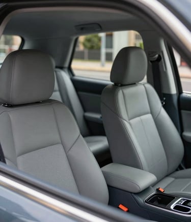 A detailed interior shot of a modern, clean, and spacious vehicle with leather seats, reflecting a premium taxi service in the British / UK region. The lighting is soft and natural, emphasizing the professional upkeep of the car. Subtle hints of slate blue accents are visible in the cabin details.