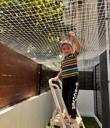 Technician carefully installing pigeon net on a balcony railing.