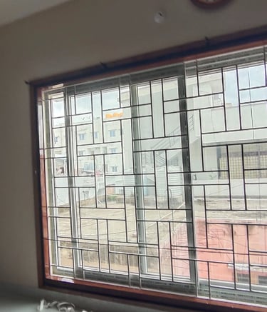 A technician from Arjilli Safety Nets installing a mosquito net on a window frame.