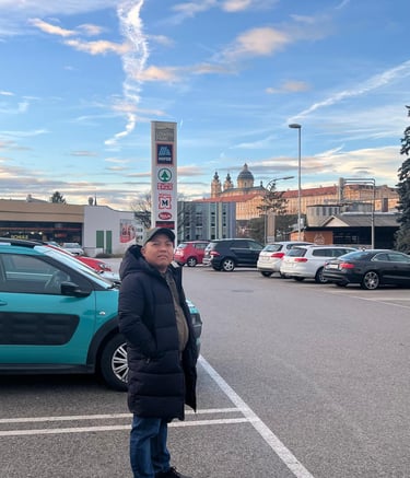 River crew stands in a busy parking lot with Melk Abbey in the background.