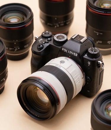 Close-up of a high-end professional camera and various prime lenses sitting on a clean, soft beige surface. The lighting is sophisticated and minimal, highlighting the precision of the equipment. Colors include dark charcoal and pearl white.