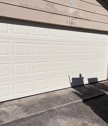 Almond sectional garage door installation on a residential brick house driveway.