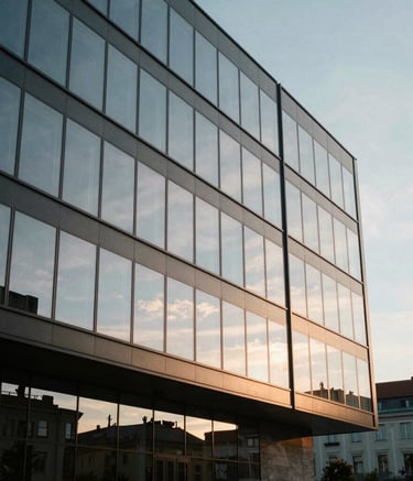 External shot of a contemporary glass office building in Bratislava, Central European / Slovak architecture, captured during the golden hour with soft sunlight reflecting off the windows, creating an aura of established success.