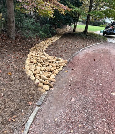 drainage bed with river rock directing water away from driveway