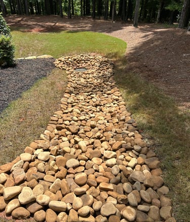 draining bed with river rock directing water away from lawn
