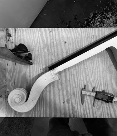 Flatlay pic of the cello neck, a plane, and caliper on the workbench before carving is complete.