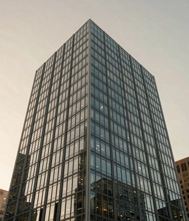 Wide-angle shot of a contemporary glass and steel office building in a US business district during golden hour, reflecting a soft beige sky.