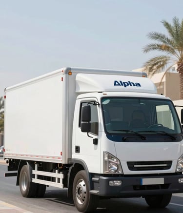 A clean, modern Alpha Furniture Moving truck parked on a sun-drenched street in Al Ain. The truck is professional and white with subtle navy blue #0F1A2A accents. The scene conveys a sense of calm reliability and professional scale.