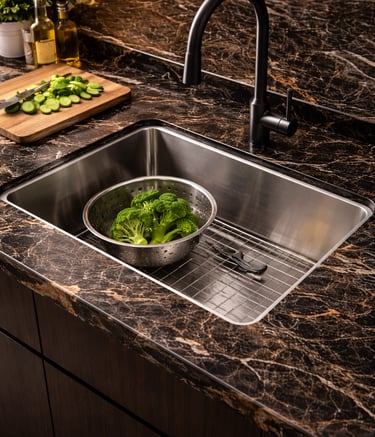 A stainless steel kitchen sink with a matte black faucet and marble countertop.
