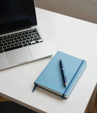 A top-down professional shot of a minimalist workspace in a North American / US home office. A high-end laptop, a Sky Blue notebook, and a Deep Blue pen sit on a clean white desk. The lighting is soft and bright, creating a calm, focused atmosphere.