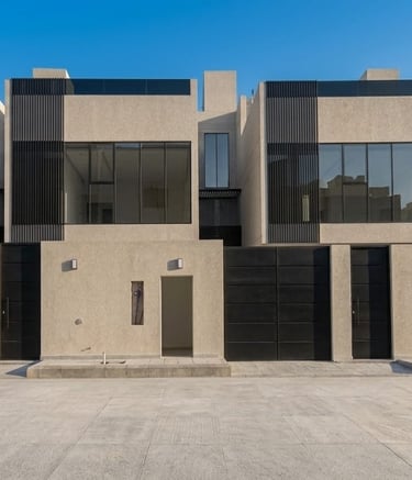 Modern luxury townhouses with minimalist concrete architecture and large glass windows under a clear sky.