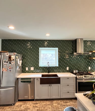 Modern kitchen featuring a green subway tile backsplash, white cabinets, and stainless steel appliances.