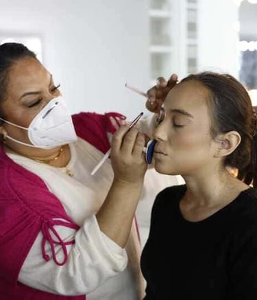 Maquilladora profesional aplicando lápiz labial a una clienta en un estudio de belleza.