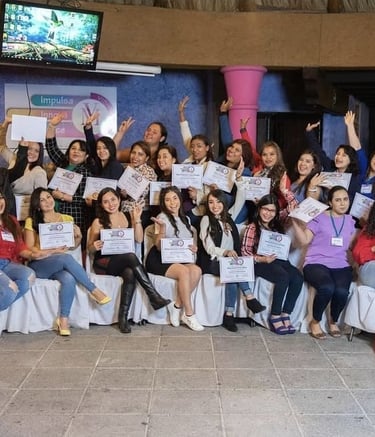 Un grupo de mujeres sonríe mientras sostienen sus certificados de graduación en un taller profesiona