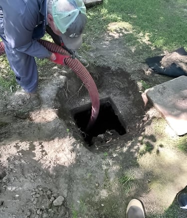 Professional technician performing a septic tank pumping service using a heavy-duty suction hose.