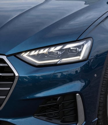 Close-up of a sleek, modern car headlight and grille, emphasizing sophisticated technology. The color palette is dominated by deep steel blue and midnight blue reflections, conveying trust and expertise.