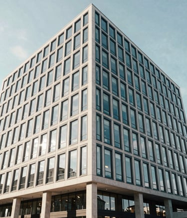 A wide-angle professional photograph of a modern glass-fronted office building in Germany during a bright day. The reflections show a clean sky. Soft Off-white and Dark Slate Blue accents in the architectural details.