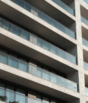 A close-up architectural shot of a contemporary residential building in a Mexican city, clean geometric lines, glass balconies reflecting a blue sky, high-end professional photography with a focus on structural detail.