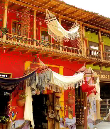 Hamacs colombiens tissés à la main exposés devant un bâtiment colonial rouge coloré dans un marché