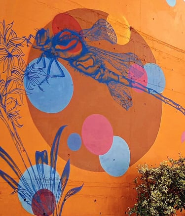 une fresque d'une libellule bleu sur fond orange