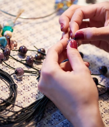 manos poniendo piedras sobre un hilo para realizar una pulsera