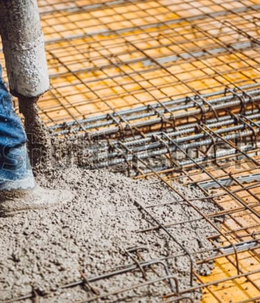 Worker holding concrete pumping hose over wire mesh.