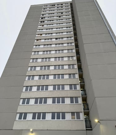 Unrenovierte Hochhausfassade mit einheitlich grauem Putz – Hebestreit Generalunternehmer