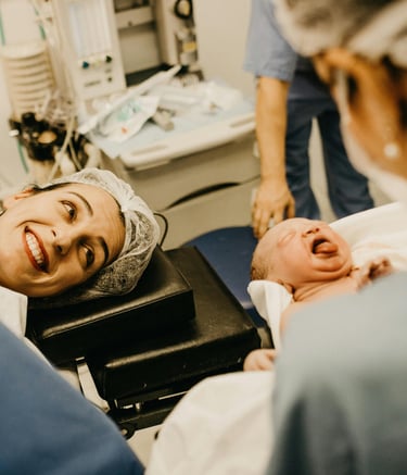 happy mother post delivery smiling seeing her baby in the doctor's hand
