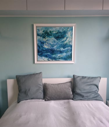 a bed with a white bed and a blue sea painting on the wall