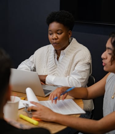 Young people sitting at a table, engaged in conversation about their work