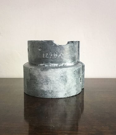 Faux lead painted pipe connector resembling a modern sculpture on a table