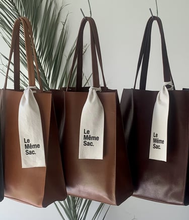 Bolsos Tote colgados en fila con degradé de colores, destacando la belleza del cuero y la elegancia 