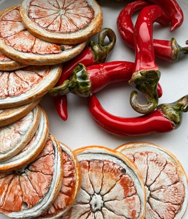 Handmade ceramic art inspired by nature with dried citrus and red chili peppers