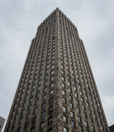 A low-angle, powerful shot of a tall New York City building with a perfectly maintained roof, emphasizing height, stability, and premium protection against a steel gray sky. Architectural photography style.