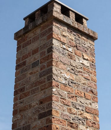 Detailed upward shot of a clean brick chimney flue, showcasing muted taupe and warm chestnut brown masonry bricks. A clear blue North American / US sky is visible through the top of the flue. Clean, professional perspective with sharp focus and natural lighting.