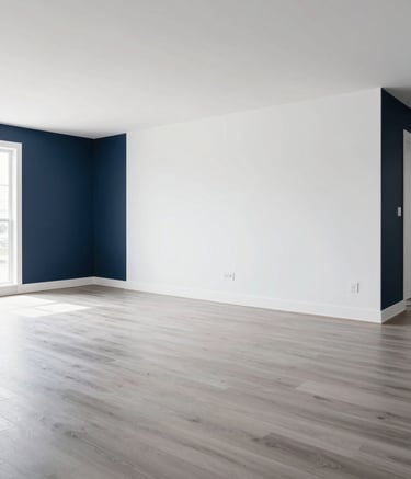 A wide-angle, bright photograph of a modern, minimalist living room in a Canadian home featuring pristine white drywall, dark blue accent elements, and light grey hardwood flooring. The space is empty and clean, showcasing high-quality workmanship.