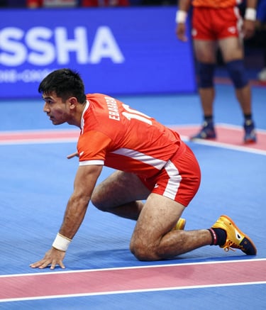 A high-action, dynamic shot of a Kabaddi raider lunging for the touchline in an indoor arena in Brampton. The player is wearing a vibrant orange-red jersey (#E8420A) contrasting against the blue court. Motion blur emphasizes speed. Crisp, energetic lighting, modern Canadian sports aesthetics.