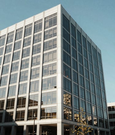 A sophisticated North American office building exterior in Spokane, Washington. The architecture features clean glass lines and steel, reflecting a bright, clear sky. The atmosphere is professional and established, shot in natural daylight.