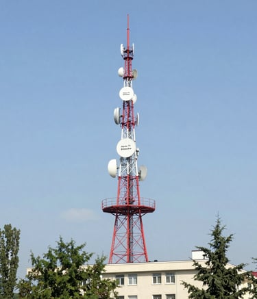 Radio tower glowing against a twilight sky, symbolizing broadcast reach.